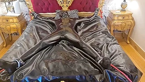 Latex-encased Woman Tied To Bed